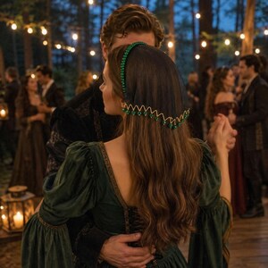 May include: A dark green velvet dress with long sleeves and a square neckline, worn with a black sheer headpiece featuring a zigzag trim adorned with small green beads. The headpiece is secured with a band of matching green beads across the crown.