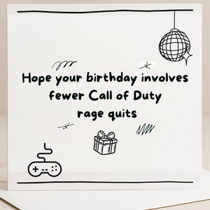 May include: A white birthday card with black illustrations. The card shows a disco ball, a gift, and a game controller. The text says, "Hope your birthday involves fewer Call of Duty rage quits."