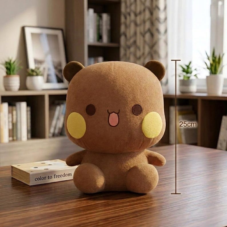 May include: A brown plush bear with yellow cheeks, dark brown eyes, and small ears. The bear is approximately 10 inches tall. The bear is sitting on a wooden table. A book with the text "color to freedom" is on the table.