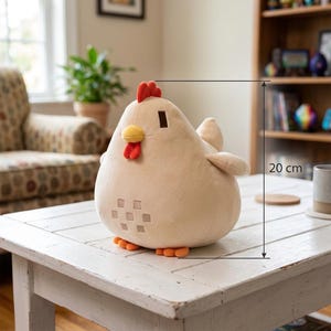 May include: A plush chicken toy in a light beige color, with a red comb and wattle, and a yellow beak. The toy has small orange feet and measures approximately 8 inches in height. It is sitting on a white wooden table.