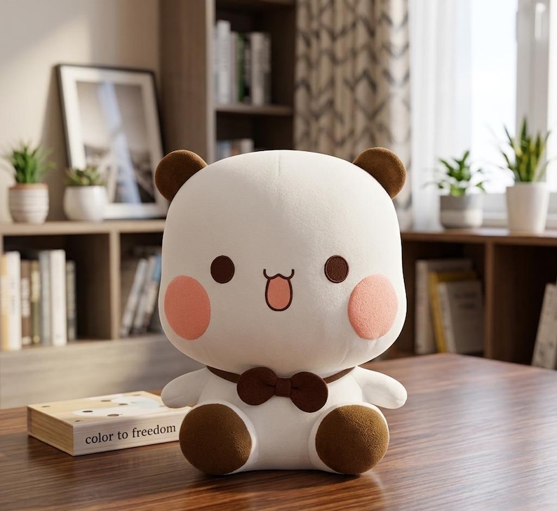 May include: A plush toy shaped like a bear with a white body, brown ears, and brown feet. It has pink cheeks, brown eyes, and a small brown bow tie. The toy is sitting on a wooden surface.