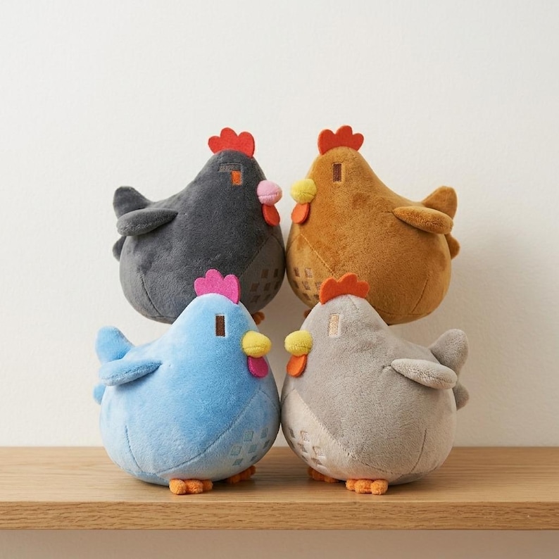 May include: Four plush chicken toys in various colors: dark gray, brown, light blue, and gray. Each chicken has a red comb, pink wattle, yellow beak, and orange feet. The chickens are sitting on a wooden shelf.