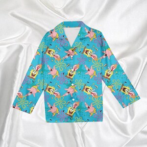 Op de afbeelding: Turquoise pyjamashirt met knopen, met een herhaald patroon van de tekenfilmfiguren SpongeBob SquarePants en Patrick Star. Het shirt met lange mouwen heeft een klassieke kraag en een knoopsluiting.
