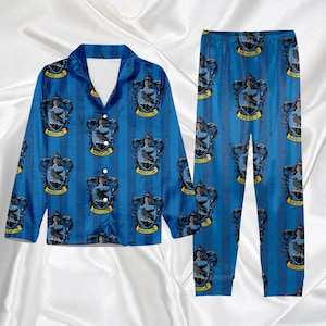 May include: Blue pajama set featuring a repeating pattern of the Ravenclaw crest. The long-sleeved top has a collared neckline and button closure. The pajama pants have a matching crest pattern.