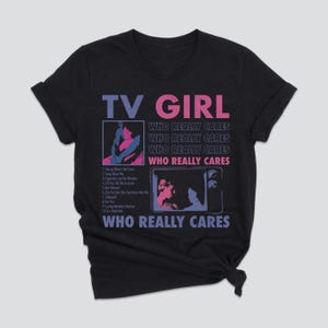 May include: Dark gray t-shirt with the text "TV GIRL" in purple and pink. The shirt features two graphic images and the text "WHO REALLY CARES" repeated multiple times. A list of song titles is also included.