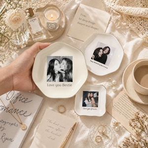 Puede incluir: Varios platos de cer&aacute;mica blanca con bordes dorados, cada uno con una fotograf&iacute;a. Uno dice "Love you Bestie", otro "Happy 10th Wedding Anniversary" y un tercero "Love you forever". La escena incluye una vela, perfume y joyas.
