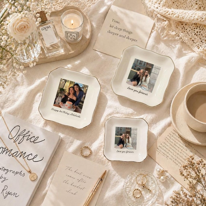 Puede incluir: Una colecci&oacute;n de bandejas decorativas de cer&aacute;mica blanca con ribete dorado, cada una con una fotograf&iacute;a. Una bandeja tiene el texto "Happy birthday Adelaide", y otras dos dicen "Love you forever". La escena incluye una vela, perfume y joyas.