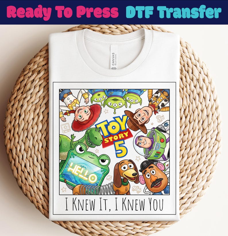May include: A white t-shirt featuring a graphic print of Toy Story characters including Woody, Buzz Lightyear, Jessie, Rex, Slinky Dog, Mr. Potato Head, and aliens. The design includes the text Toy Story 5 and the phrase I KNEW IT, I KNEW YOU.