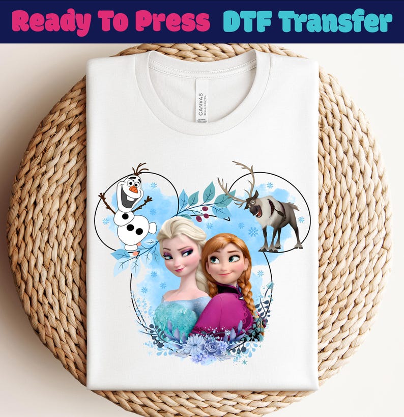 May include: White t-shirt featuring a colorful graphic of characters from the animated movie Frozen, including Elsa, Anna, Olaf, and Sven. The design is set within a Mickey Mouse-shaped outline with blue accents and the text "Ready To Press DTF Transfer" at the top.