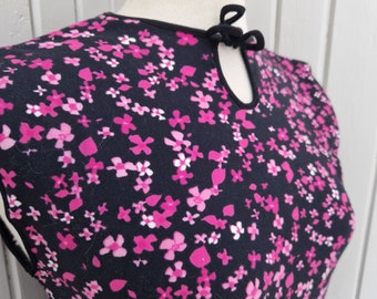 May include: A black sleeveless dress with a pink floral print and a keyhole neckline with a black bow tie.