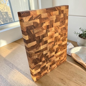 Handmade walnut end grain cutting board on kitchen table, thick butcher block chopping board made from natural walnut wood, premium wooden cutting board for kitchen, durable chef board for cutting meat, vegetables and food preparation