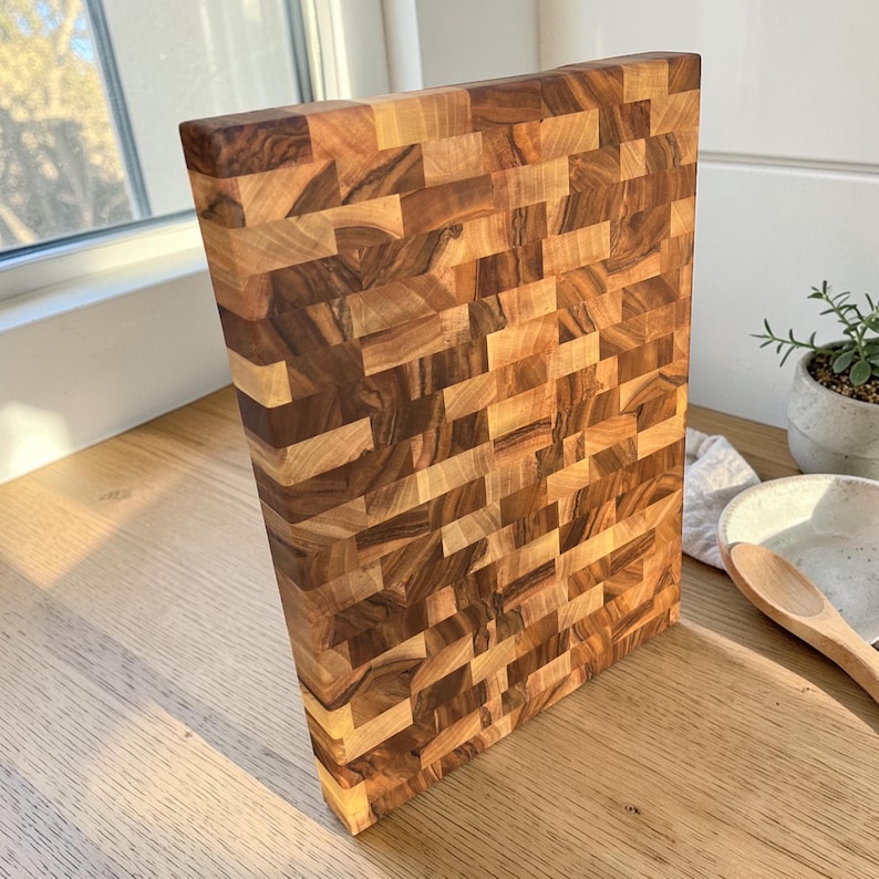 Handmade walnut end grain cutting board on kitchen table, thick butcher block chopping board made from natural walnut wood, premium wooden cutting board for kitchen, durable chef board for cutting meat, vegetables and food preparation