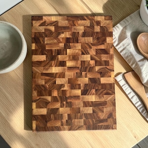 Handmade walnut end grain cutting board on kitchen table, thick butcher block chopping board made from natural walnut wood, premium wooden cutting board for kitchen, durable chef board for cutting meat, vegetables and food preparation