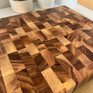 Handmade walnut end grain cutting board on kitchen table, thick butcher block chopping board made from natural walnut wood, premium wooden cutting board for kitchen, durable chef board for cutting meat, vegetables and food preparation