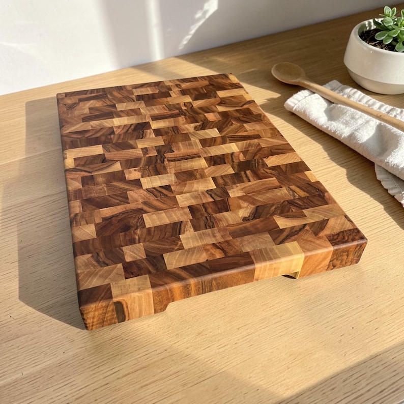 Handmade walnut end grain cutting board on kitchen table, thick butcher block chopping board made from natural walnut wood, premium wooden cutting board for kitchen, durable chef board for cutting meat, vegetables and food preparation