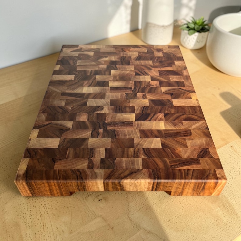 Handmade walnut end grain cutting board on kitchen table, thick butcher block chopping board made from natural walnut wood, premium wooden cutting board for kitchen, durable chef board for cutting meat, vegetables and food preparation