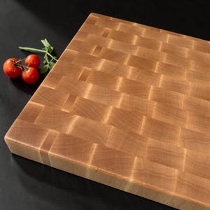 Angled close view of the maple end grain butcher block with cherry tomatoes on a dark background