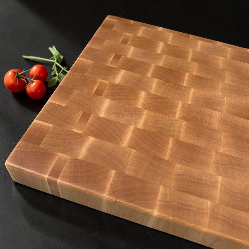 Angled close view of the maple end grain butcher block with cherry tomatoes on a dark background