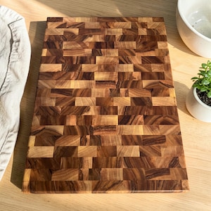 Handmade walnut end grain cutting board on kitchen table, thick butcher block chopping board made from natural walnut wood, premium wooden cutting board for kitchen, durable chef board for cutting meat, vegetables and food preparation