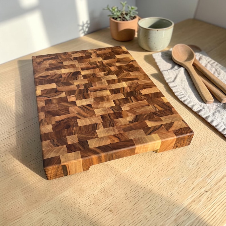 Handmade walnut end grain cutting board on kitchen table, thick butcher block chopping board made from natural walnut wood, premium wooden cutting board for kitchen, durable chef board for cutting meat, vegetables and food preparation