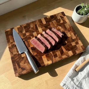 Handmade walnut end grain cutting board on kitchen table, thick butcher block chopping board made from natural walnut wood, premium wooden cutting board for kitchen, durable chef board for cutting meat, vegetables and food preparation