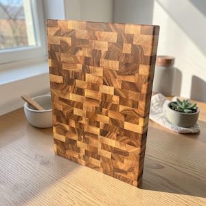 Handmade walnut end grain cutting board on kitchen table, thick butcher block chopping board made from natural walnut wood, premium wooden cutting board for kitchen, durable chef board for cutting meat, vegetables and food preparation