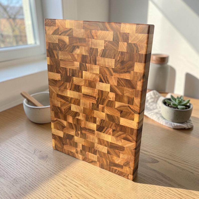 Handmade walnut end grain cutting board on kitchen table, thick butcher block chopping board made from natural walnut wood, premium wooden cutting board for kitchen, durable chef board for cutting meat, vegetables and food preparation