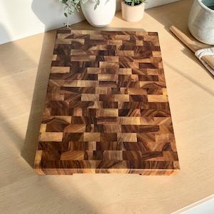 Handmade walnut end grain cutting board on kitchen table, thick butcher block chopping board made from natural walnut wood, premium wooden cutting board for kitchen, durable chef board for cutting meat, vegetables and food preparation