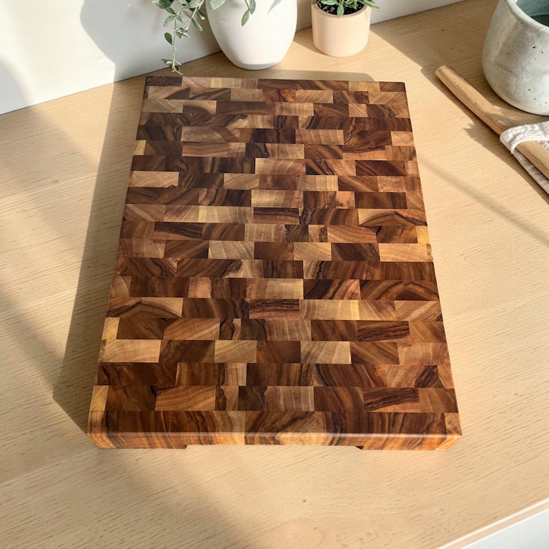 Handmade walnut end grain cutting board on kitchen table, thick butcher block chopping board made from natural walnut wood, premium wooden cutting board for kitchen, durable chef board for cutting meat, vegetables and food preparation