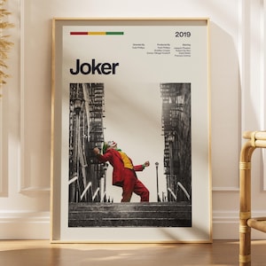 May include: A vertical poster featuring the 2019 film Joker. The design includes the title, production credits, and a black and white photograph of a person in a red suit and yellow vest dancing on stairs between buildings, framed in a light border.