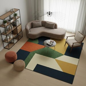 May include: A modern living room featuring a curved beige sofa, a geometric patterned rug in shades of blue, green, orange, and yellow, and a small round coffee table. A wooden bookshelf and a chair with a light-colored cushion are also present.