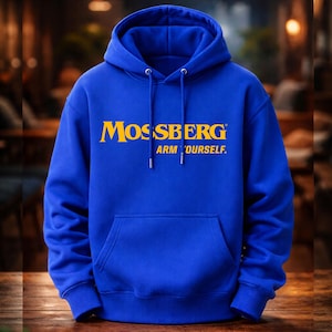 Op de afbeelding: Een koningsblauwe hoodie met een voorzak en een capuchon met trekkoord. De hoodie toont het woord "MOSSBERG" in gele blokletters, met "ARM YOURSELF." eronder gedrukt. De achtergrond is wazig.