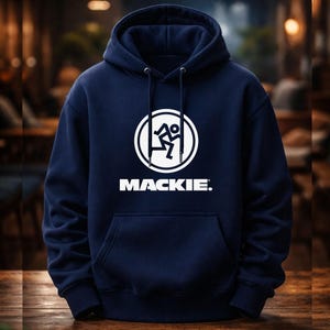 May include: A navy blue hooded sweatshirt featuring a white circular logo with a running figure and the word "MACKIE." underneath. It has a front pocket and a drawstring hood.