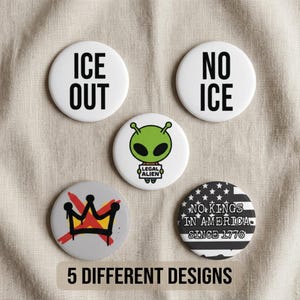 Puede incluir: Una colección de cinco botones redondos blancos con varios diseños y texto. Los botones presentan frases como "ICE OUT" y "NO ICE", un gráfico de alienígena, un diseño de corona y un diseño patriótico con el texto "NO KINGS IN AMERICA SINCE 1776".