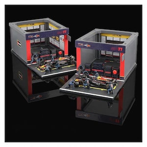 Puede incluir: Dos dioramas en miniatura de garaje de F&oacute;rmula 1. Cada uno presenta una estructura de garaje gris y roja con un coche de carreras, figuras en miniatura y herramientas. Los garajes est&aacute;n sobre una base negra, con el texto "SP11" visible en la parte superior.