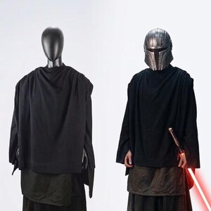 Op de afbeelding: Een kostuumset bestaande uit een zwarte tuniek en een donkerbruine rok, geïnspireerd op The Stranger Qimir uit Star Wars Acolyte. De outfit bevat een zwarte gedrapeerde top, een gelaagde bruine rok, een metalen helm en een rood lichtzwaard-rekwisiet.