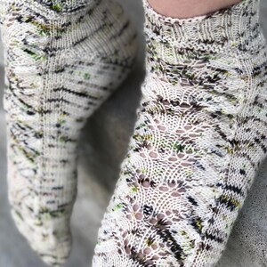 May include: A pair of white and green patterned socks with a lacy design. The socks are knitted and have a short ankle length.