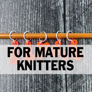 Può includere: Cinque marcapunti arancioni con anelli argentati su un'ago da maglia in legno. I marcapunti hanno il testo "FOR MATURE KNITTERS".
