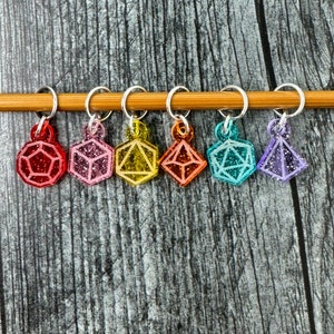 Può includere: Sei marcatori di punto in plastica scintillanti e colorati a forma di dado, appesi a un'ago da maglia in bambù. I marcatori di punto sono rosso, rosa, giallo, verde, blu e viola.