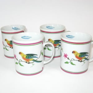 May include: Set of four white ceramic mugs with a colorful parrot design. Each mug features a different parrot with pink flowers and green leaves.