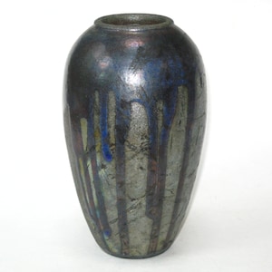 May include: A dark, glazed ceramic vase with a rounded body and a narrow neck. The vase has a metallic sheen with streaks of blue, red, and yellow running down its surface. The overall effect is a blend of dark and vibrant colors.