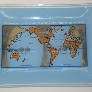 May include: A blue and white glass ashtray with a world map design. The map shows the locations of various satellite stations and the text "COMMUNICATIONS SATELLITE CORPORATION" and "STH ANNIVERSARY" and "FEBRUARY 1, 1968".