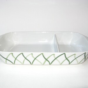 May include: A white ceramic divided serving dish with a green and white geometric pattern. The dish has two sections.