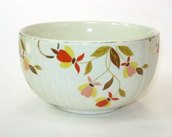 May include: A white ceramic mixing bowl with a floral pattern in shades of yellow, orange, pink, and brown. The bowl has a gold rim and a fluted design.