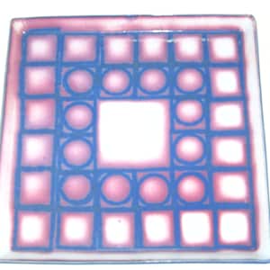 May include: A square ceramic tile with a geometric design. The tile is white with a pink and blue pattern of squares and circles.