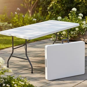 May include: A white rectangular folding table with gray metal legs is set up outdoors. A matching folded table with a handle stands nearby. The scene is set on a stone patio with greenery and flowers in the background.