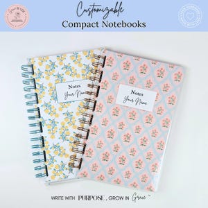 May include: Two spiral-bound compact notebooks with clear covers. One features a yellow floral pattern, the other a pink floral pattern with a blue lattice. Both have a white label reading Notes Your Name. The text Customizable Compact Notebooks is visible.