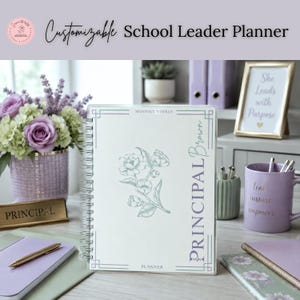 Könnte beinhalten: Ein spiralgebundener Planer mit weißem Einband, einer grünen Blumenillustration und dem Text Principal Brown. Der Planer enthält die Wörter Monthly Weekly und Planner. Er ist neben einem lila Becher, einem Stift und einem Namensschild abgebildet.