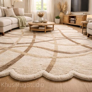 Puede incluir: Una alfombra grande, de color crema, con un borde festoneado y un patrón geométrico de líneas marrones que se cruzan. La alfombra está en un salón con un sofá, una mesa de centro y un televisor.