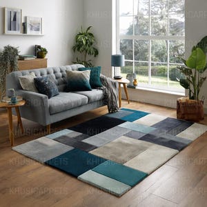 Peut inclure: Un tapis moderne avec un design géométrique dans les tons de gris, de bleu sarcelle et de bleu marine. Le tapis est rectangulaire et présente un motif patchwork. La pièce comprend également un canapé gris, des coussins et des plantes.